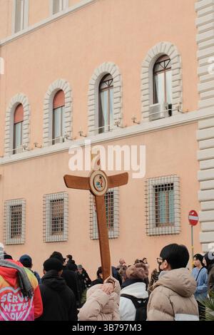 Religiöse Prozession in Rom mit einer Gruppe von Pilgern, die während des Jubiläums der Pilger der Hoffnung Rom 2025 ein großes Holzkreuz durch die historische Straße tragen Stockfoto