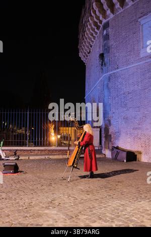 Straßenmusiker, die nachts auf der kopfsteingepflasterten römischen Brücke unter der Ampel im romantischen historischen Stadtambiente Rom Italien auftreten. Hochwertige Fotos Stockfoto