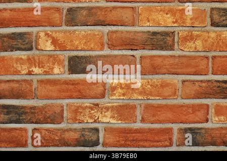 Authentische Nahaufnahme einer rustikalen roten Ziegelwand mit natürlichen Farbveränderungen und einer gruseligen Textur; perfekter Hintergrund oder Designelement. Stockfoto