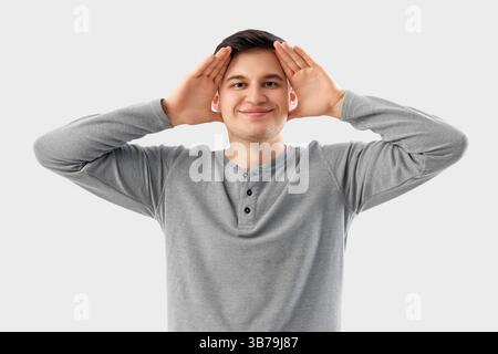 Junger Mann, der Gesichtsbauübung auf hellem Hintergrund macht Stockfoto