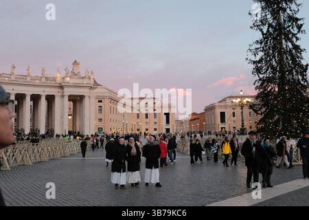 Petersplatz bei Sonnenuntergang während der Weihnachtszeit mit geschmückten Pilgermassen und sanftem pastellfarbenem Himmel um die Kolonnaden der Vatikanstadt. Hochwertige Fotos Stockfoto