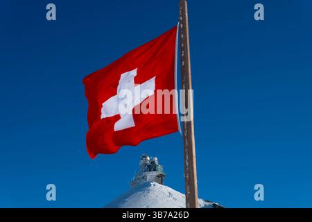 Sphinx-Observatorium auf dem Jungfraujoch und Schweizer Flagge an einem sonnigen Wintertag im Kanton Bern in der Schweiz. Stockfoto
