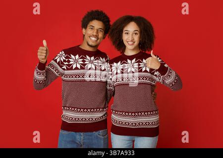 Frohe Weihnachten und frohes neues Jahr. Das fröhliche junge afroamerikanische Paar zeigt die Daumen hoch Stockfoto