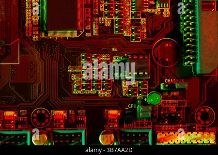 Nahaufnahme eines Motherboards mit integrierten Schaltungen und Anschlüssen unter roter und grüner Beleuchtung, wodurch ein High-Tech, komplexer und futuristischer Eindruck entsteht Stockfoto