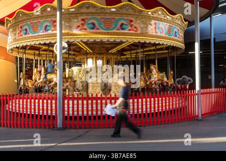 Das Bild einer Frau ist verschwommen, als sie am Karussell im Sydney Luna Park vorbeiläuft Stockfoto