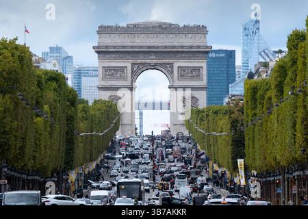 Die geschäftige Champs-Elysees Avenue in Paris mit starkem Verkehr, dem berühmten Arc de Triomphe im Zentrum und den Wolkenkratzern La Defense im Hintergrund Stockfoto