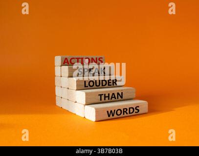 Taten sprechen lauter als Wörter. Holzblöcke mit Worten Aktionen sprechen lauter als Worte. Wunderschöner orangefarbener Hintergrund. Unternehmen und Aktionen Co Stockfoto