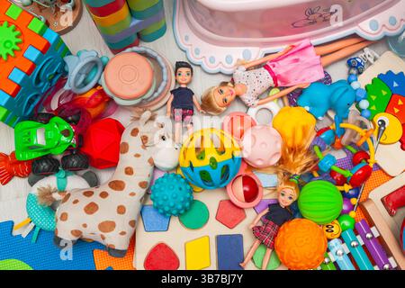 Ein Haufen verschiedener Kinderspielzeuge, verstreut auf einer Spielmatte. Stockfoto