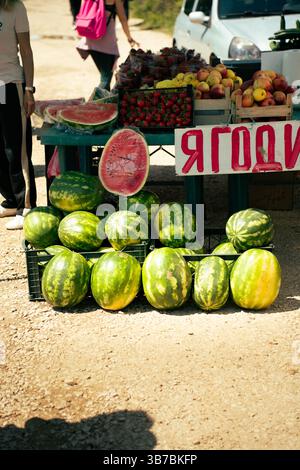 Obststand im Freien, der Wassermelonen, Erdbeeren und Äpfel auf einem ländlichen Markt in Bulgarien verkauft Stockfoto