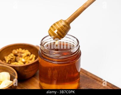 Honig tropft aus dem Honiglöffel in einem Glas Honig Stockfoto