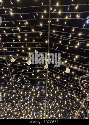Das zauberhafte Baldachin aus funkelnden Lichtern vor offenem Nachthimmel fängt den Zauber und das Wunder der abendlichen Festlichkeiten und Feierlichkeiten ein. Stockfoto