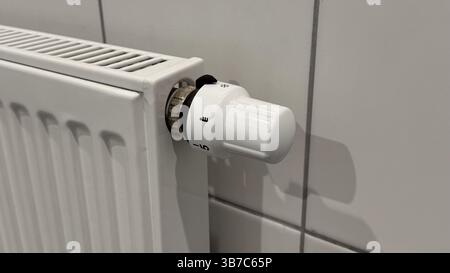 Weißer Heizkörper mit Thermostat in modernen Wohnräumen, der Temperaturregelung und Energieeffizienz in modernen Heizsystemen bietet. Stockfoto