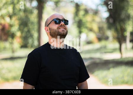 Porträt eines Mannes mit Bart und Sonnenbrille, der nach oben blickt. Stockfoto