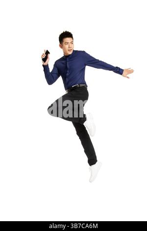 Geschäftsmann springt mitten in der Luft, während er ein Smartphone hält. Stockfoto