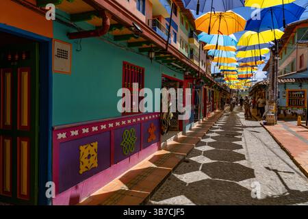 Farbenfrohe Sonnenschirme spenden Schatten auf der Plazoleta de los Zócalos, einer Einkaufsstraße in Guatape, Kolumbien. Stockfoto
