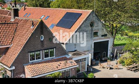 25. April 2025 - den Briel-Niederlande: Traditionelle niederländische Häuser mit roten Ziegeldächern und Solarpaneelen in den Briel, einer vollständig ummauerten historischen Festung Stockfoto