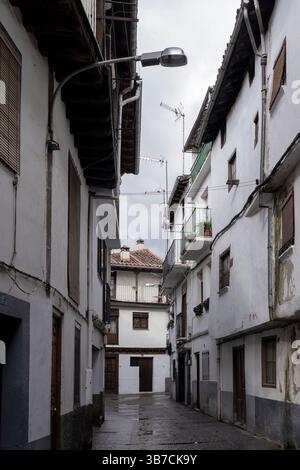 Traditionelle Architektur mit weißen Fassaden, Holzbalkonen und Fliesendächern zeichnet eine malerische Gasse in Candelario aus Stockfoto