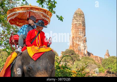 Thailand-Feb 09 2024: Touristen nehmen an einem heißen Nachmittag in der Nähe des alten Königspalastes an Elefanten-zurück-Touren Teil, geführt von ihren Pflegern. Stockfoto