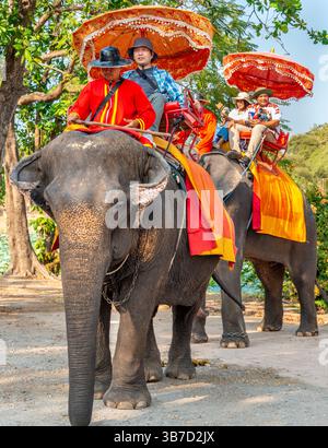 Thailand-Feb 09 2024: Touristen nehmen an einem heißen Nachmittag in der Nähe des alten Königspalastes an Elefanten-zurück-Touren Teil, geführt von ihren Pflegern. Stockfoto