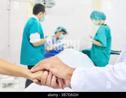Freundliche männliche Hände, die weibliche Hand halten, um Ermutigung und Empathie zu fördern. Vertrauen Anfeuern und Unterstützung, medizinische Ethik Konzept. OP-Saal bac Stockfoto