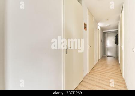 Ein eleganter, moderner Korridor mit minimalistischen weißen Wänden und Holzfußboden. Das unauffällige Design betont Einfachheit und Geräumigkeit. Stockfoto