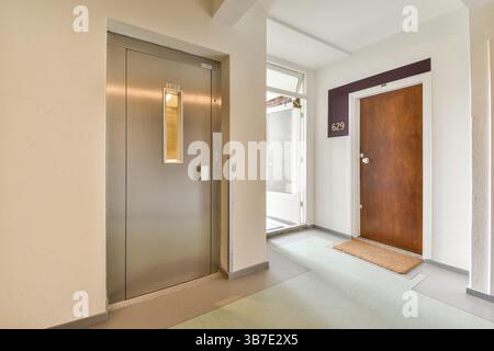 Ein eleganter Eingangsbereich mit Aufzug und Holztür, moderne Designelemente und glatter Bodenbelag schaffen eine einladende Atmosphäre. Stockfoto