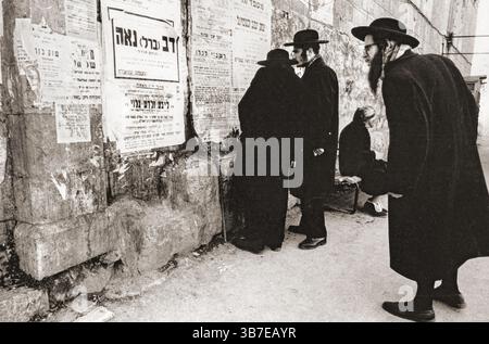 Ultraorthodoxe jüdische Männer lesen Schilder auf Hebräisch und Jiddisch an einer MEA Shearim-Sektion von Jerusalem. In Israel um 1975 Stockfoto
