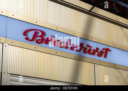 Nahaufnahme eines Schilds im Retro-Stil „Bratwurst“ an einer goldenen Metallwand, das das traditionelle deutsche Fast Food und Street Food in Berlin repräsentiert. Berlin Stockfoto