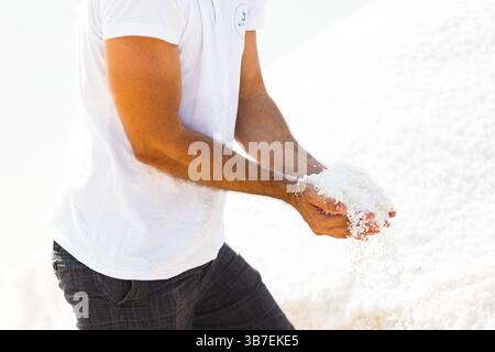 Traditionelle Salzernte in Küstensalzpfannen. Die Arbeiter sammeln von Hand Meersalz, das durch Sonnenverdunstung gebildet wird, und erzeugen dabei markantes weißes Salz. Stockfoto