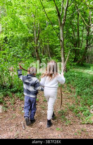 Junge und Mädchen auf einem Weg durch die Wälder des Stanmer Park in Spring Brighton Großbritannien : Credit Simon Dack Stockfoto