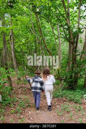 Junge und Mädchen auf einem Weg durch die Wälder des Stanmer Park in Spring Brighton Großbritannien : Credit Simon Dack Stockfoto