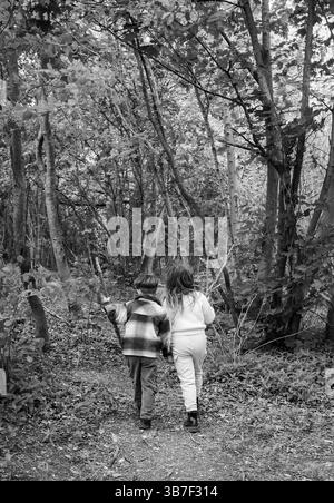 Junge und Mädchen auf einem Weg durch die Wälder des Stanmer Park in Spring Brighton Großbritannien : Credit Simon Dack Stockfoto