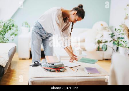 Student organisiert Studienmaterialien zu Hause in gemütlichem Raum Stockfoto