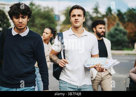 Gruppe junger Studenten, die gemeinsam in einer städtischen Umgebung spazieren Stockfoto