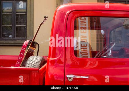 Ein alter Pickup-Truck, der auf einer alten Straße im Inneren geparkt wurde, mit Gitarre auf dem Eimer. Stockfoto