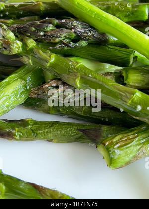 Nahaufnahme gegrillter grüner Spargel, serviert auf einem sauberen weißen Teller. Gesundes saisonales Gemüsegericht Stockfoto