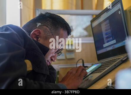 (250506) -- LHASA, 6. Mai 2025 (Xinhua) -- Lhapa Dondrup lädt Produktinformationen in das Internet bei dem Unternehmen in Lhasa, südwestchinesischer autonomer Region Xizang, 5. Mai 2025 hoch. Lhapa Dondrup, ein 24-jähriger Mann, der in Lhasa geboren wurde, leidet seit seiner Kindheit an Osteogenesis imperfecta (OI), allgemein bekannt als brüchige Knochenerkrankung. Als Erwachsener steht er unter einem Meter groß und verlässt sich auf Krücken und elektrischen Rollstuhl für Mobilität. Trotz dieser Herausforderungen träumt Lhapa davon, Fotograf zu werden. 2021 schloss er sich einem Kulturmedienunternehmen an, das von Einzelpersonen mit gegründet wurde Stockfoto