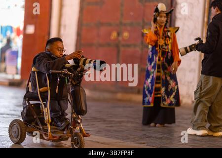 (250506) -- LHASA, 6. Mai 2025 (Xinhua) -- Lhapa Dondrup macht Fotos in der Barkhor Street in Lhasa, südwestchinesischer Autonomen Region Xizang, 29. April 2025. Lhapa Dondrup, ein 24-jähriger Mann, der in Lhasa geboren wurde, leidet seit seiner Kindheit an Osteogenesis imperfecta (OI), allgemein bekannt als brüchige Knochenerkrankung. Als Erwachsener steht er unter einem Meter groß und verlässt sich auf Krücken und elektrischen Rollstuhl für Mobilität. Trotz dieser Herausforderungen träumt Lhapa davon, Fotograf zu werden. 2021 trat er einem Kulturmedienunternehmen bei, das von Menschen mit körperlicher Behinderung gegründet wurde Stockfoto