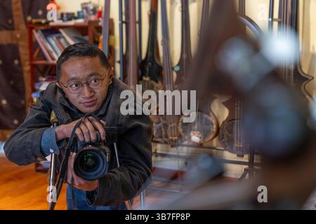 (250506) -- LHASA, 6. Mai 2025 (Xinhua) -- Lhapa Dondrup fotografiert das Zhanian, ein traditionelles tibetisches Streichinstrument, bei der Firma in Lhasa, südwestchinesischer Autonomen Region Xizang, 6. Mai 2025. Lhapa Dondrup, ein 24-jähriger Mann, der in Lhasa geboren wurde, leidet seit seiner Kindheit an Osteogenesis imperfecta (OI), allgemein bekannt als brüchige Knochenerkrankung. Als Erwachsener steht er unter einem Meter groß und verlässt sich auf Krücken und elektrischen Rollstuhl für Mobilität. Trotz dieser Herausforderungen träumt Lhapa davon, Fotograf zu werden. 2021 wechselte er zu einem Kulturmedienunternehmen Stockfoto
