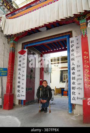 (250506) -- LHASA, 6. Mai 2025 (Xinhua) -- Lhapa Dondrup ist am Eingang des Unternehmens in Lhasa, südwestchinesischer Autonomen Region Xizang, 5. Mai 2025 abgebildet. Lhapa Dondrup, ein 24-jähriger Mann, der in Lhasa geboren wurde, leidet seit seiner Kindheit an Osteogenesis imperfecta (OI), allgemein bekannt als brüchige Knochenerkrankung. Als Erwachsener steht er unter einem Meter groß und verlässt sich auf Krücken und elektrischen Rollstuhl für Mobilität. Trotz dieser Herausforderungen träumt Lhapa davon, Fotograf zu werden. 2021 schloss er sich einem Kulturmedienunternehmen an, das von Menschen mit körperlicher Behinderung gegründet wurde Stockfoto