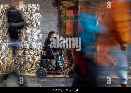 (250506) -- LHASA, 6. Mai 2025 (Xinhua) -- Lhapa Dondrup macht Fotos in der Barkhor Street in Lhasa, südwestchinesischer Autonomen Region Xizang, 29. April 2025. Lhapa Dondrup, ein 24-jähriger Mann, der in Lhasa geboren wurde, leidet seit seiner Kindheit an Osteogenesis imperfecta (OI), allgemein bekannt als brüchige Knochenerkrankung. Als Erwachsener steht er unter einem Meter groß und verlässt sich auf Krücken und elektrischen Rollstuhl für Mobilität. Trotz dieser Herausforderungen träumt Lhapa davon, Fotograf zu werden. 2021 trat er einem Kulturmedienunternehmen bei, das von Menschen mit körperlicher Behinderung gegründet wurde Stockfoto
