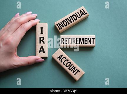 IRA - Symbol für individuelles Abgangskonto. Konzeptwort IRA auf Holzblöcken. Geschäftsmann Hand. Wunderschöner graugrüner Hintergrund. Geschäftliche und IRA-Kontrakte Stockfoto
