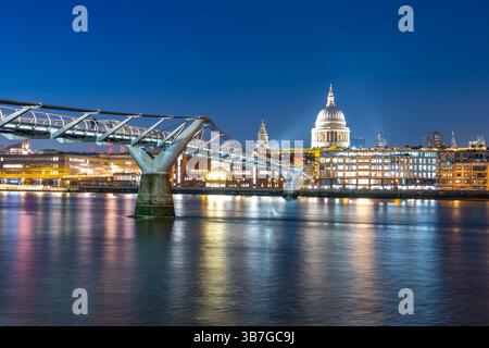 Atemberaubender Abend an der Themse mit Millenium Bridge, beleuchtet vor dem Hintergrund der St. Paul's Cathedral. Die Lichter der Stadt spiegeln sich wunderbar auf dem Wasser. Stockfoto