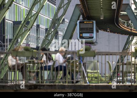 Der Zug der Wuppertaler Schwebebahn fährt entlang der Wupper, an der Haltestelle Hauptbahnhof, Terrasse Cafe23 auf einer kleinen Brücke über den Fluss, Nord R Stockfoto