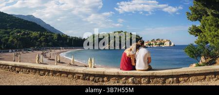 Ein junges Paar umarmt und schaut auf die Insel Sveti Stefan in Montenegro Stockfoto