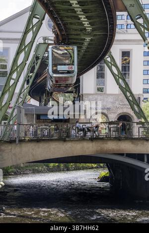 Der Zug der Wuppertaler Schwebebahn fährt entlang der Wupper, an der Haltestelle Hauptbahnhof, Terrasse Cafe23 auf einer kleinen Brücke über den Fluss, Nord R Stockfoto
