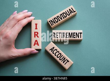 IRA - Symbol für individuelles Abgangskonto. Konzeptwort IRA auf Holzblöcken. Geschäftsmann Hand. Wunderschöner graugrüner Hintergrund. Geschäftliche und IRA-Kontrakte Stockfoto