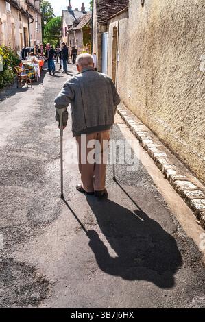 Alter Mann mit Gehstöcken, der in engen Straßen pausiert - Angles-sur-l'Anglin, Vienne (86), Frankreich. Stockfoto