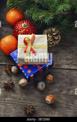 Zwei kleine Schachteln mit Geschenken auf dem Hintergrund von Mandarine, Fichtenzweig, Haselnüssen und Gewürzen Stockfoto