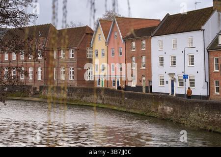 Die Menschen schlendern entlang des Flusses Wensum in Norwich, Großbritannien, und genießen den Blick auf die historischen Gebäude am Ufer. Stockfoto